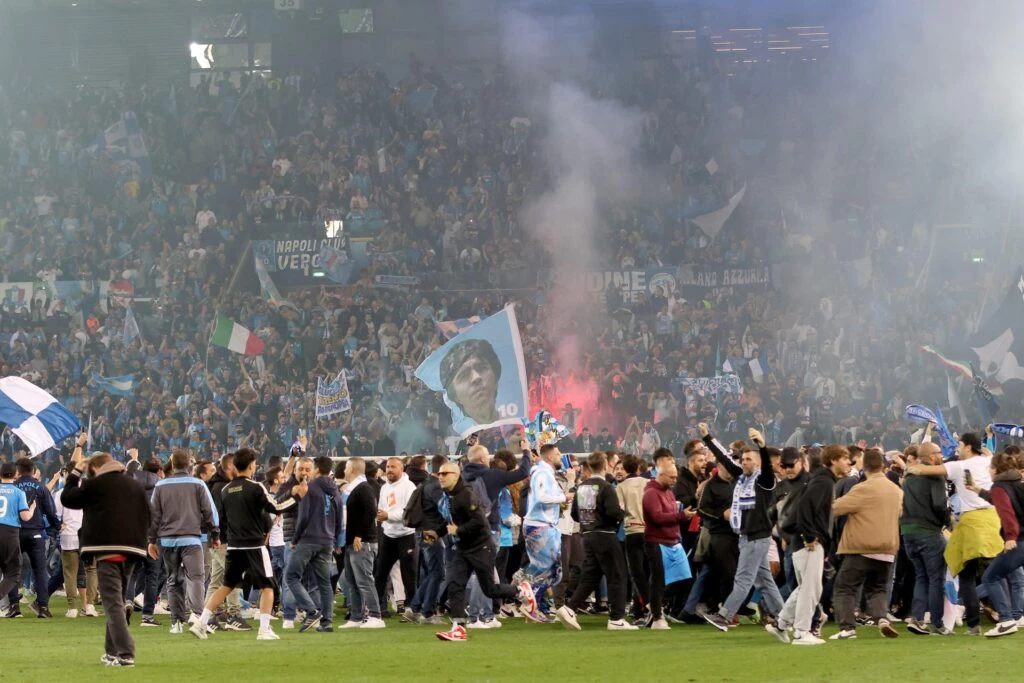 Los jugadores y los hincha de Napoli celebran en la cancha de Udinese, durante los festejos por el título de su equipo