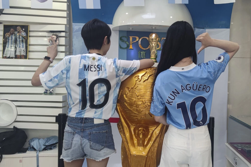 Las fans chinas de Messi y Kun Agüero posaron junto a una escultura del trofeo de la Copa del Mundo en un local de China Post habilitado como tienda oficial de la selección argentina. 